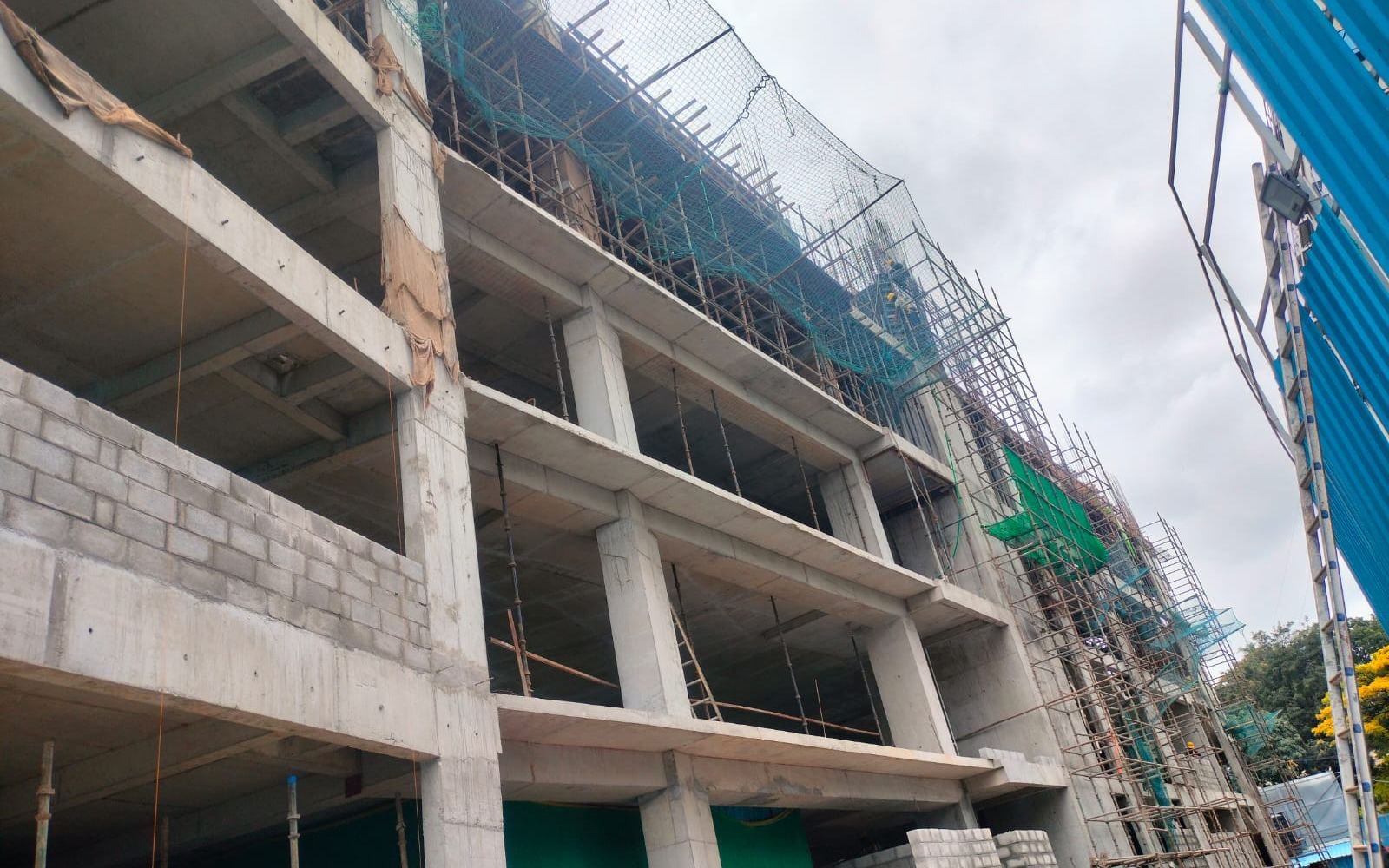 Reinforced concrete frame under construction with scaffolding and safety netting